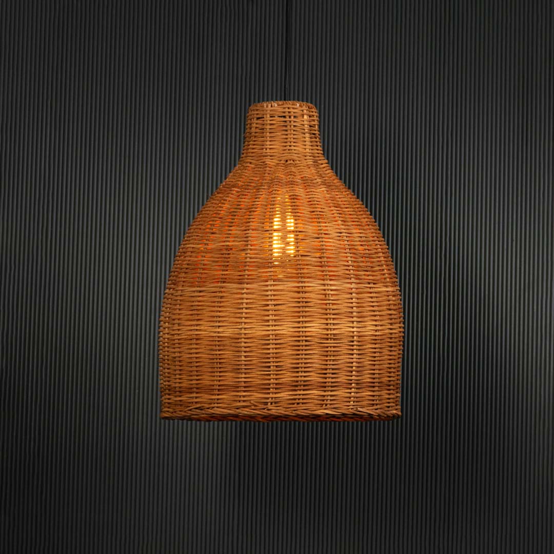 Brown rattan pendant light with handwoven bamboo shade turned on glowing softly against plain black background.