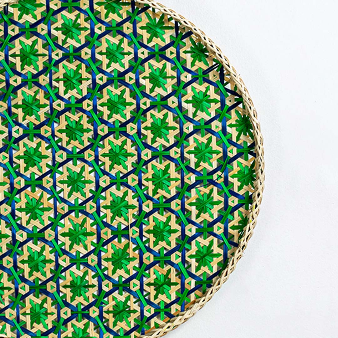 Closeup of green woven bamboo wall plate showing intricate handwoven pattern and detailed craftsmanship in natural fibers.
