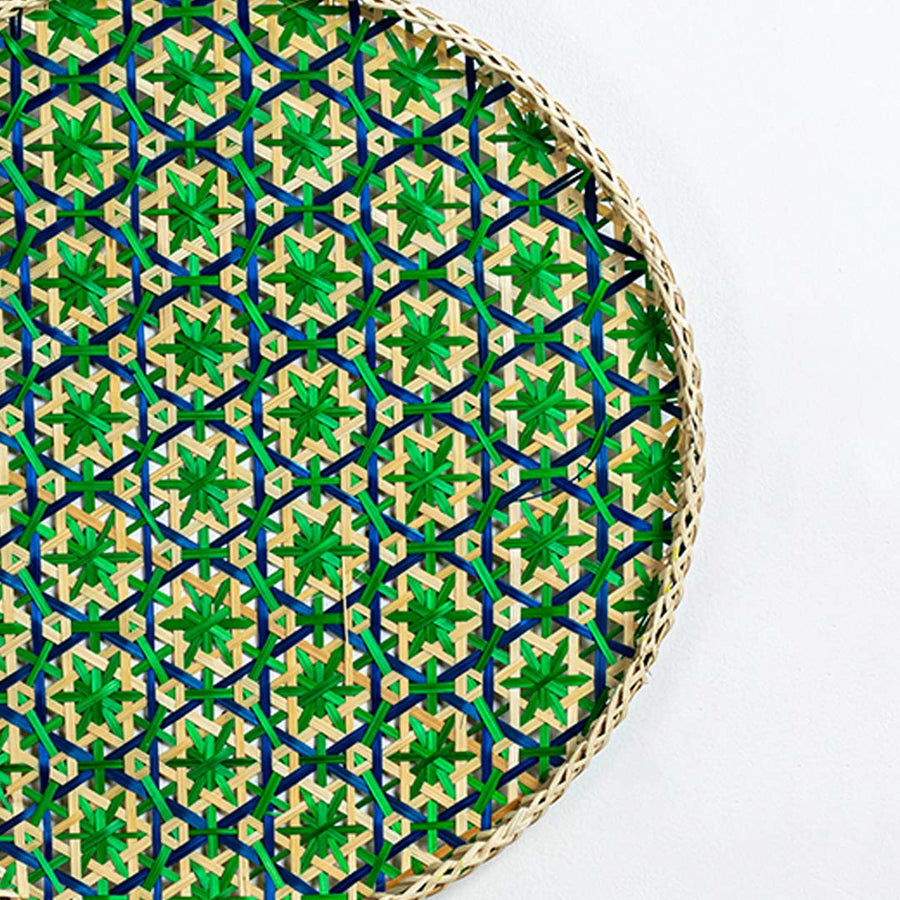 Closeup of green woven bamboo wall plate showing intricate handwoven pattern and detailed craftsmanship in natural fibers.