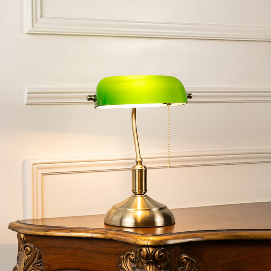 Elegant green glass and brass banker table lamp glowing warmly on white background for sophisticated interiors.