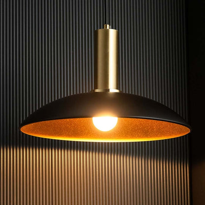 Closeup of black metal pendant light with warm glowing bulb gold inner reflector and sleek modern ceiling light design.