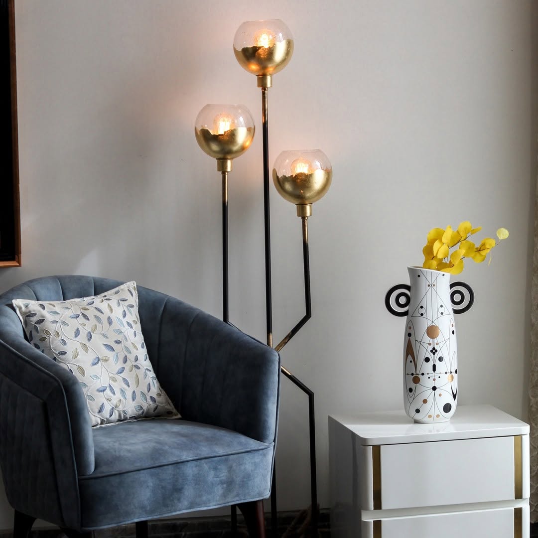 White abstract ceramic vase with black and gold geometric design styled in a minimal scene adding artistic modern charm to decor.