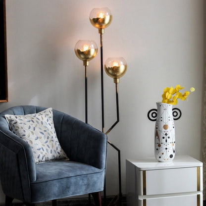 White abstract ceramic vase with black and gold geometric design styled in a minimal scene adding artistic modern charm to decor.