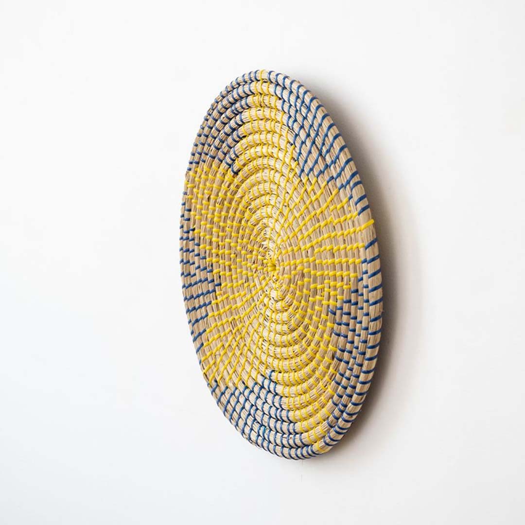Handwoven wicker wall plate side view showing yellow navy and beige woven star texture for boho wall decor.
