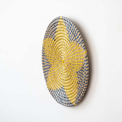 Handwoven wicker wall plate side view showing yellow navy and beige woven star texture for boho wall decor.