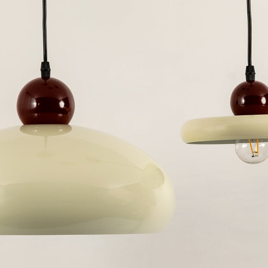 Cream metal pendant lights with burgundy accents illuminated to showcase modern decorative ceiling lighting elegance.