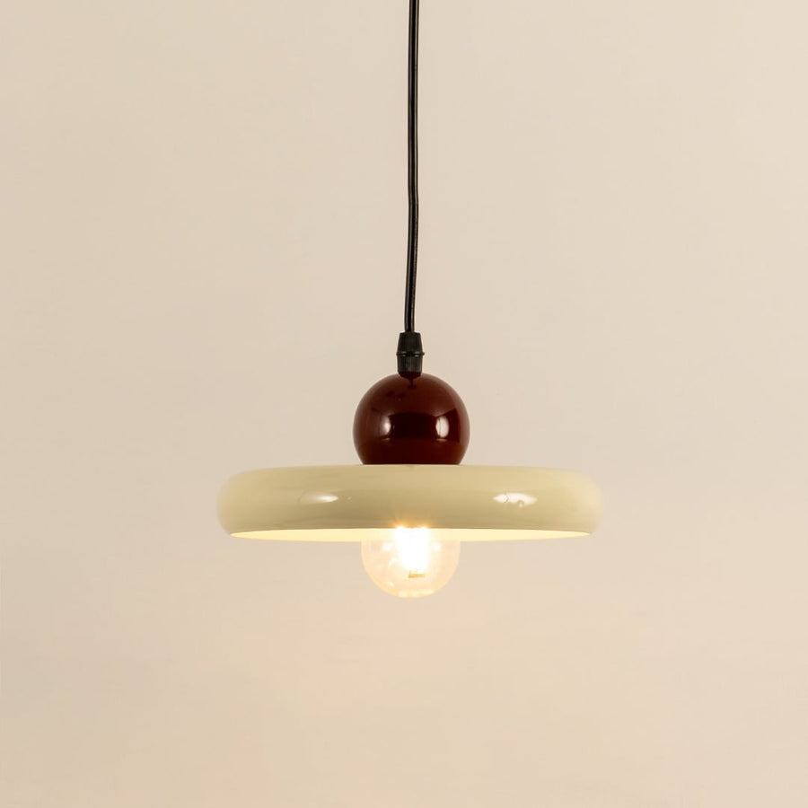 Cream metal pendant light with burgundy accent illuminated to showcase modern ceiling lighting and warm ambient glow.