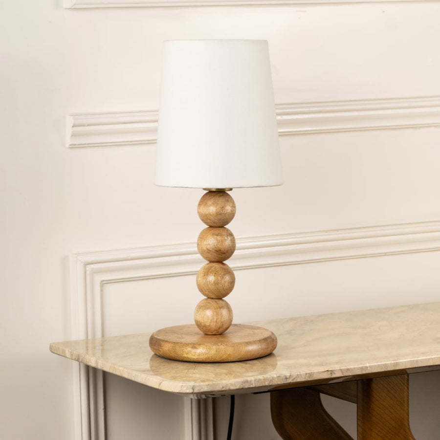 Natural wood table lamp with sculpted bead base and white fabric shade for warm organic interior decor styling.