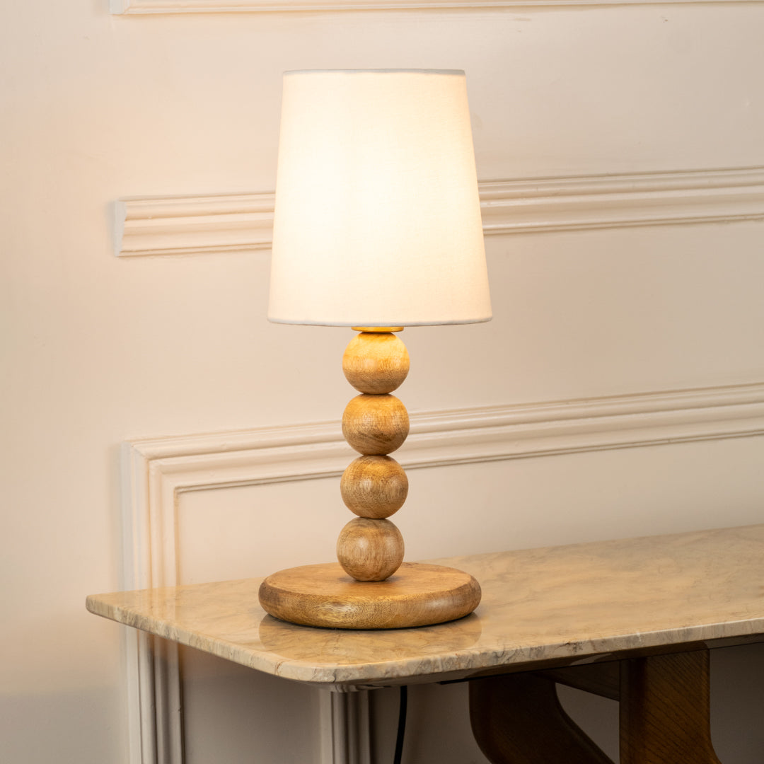 Closeup of table lamp with white fabric shade and sculpted base showcasing elegant design and warm lighting for bedroom decor styling.