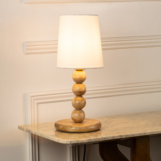Closeup of table lamp with white fabric shade and sculpted base showcasing elegant design and warm lighting for bedroom decor styling.