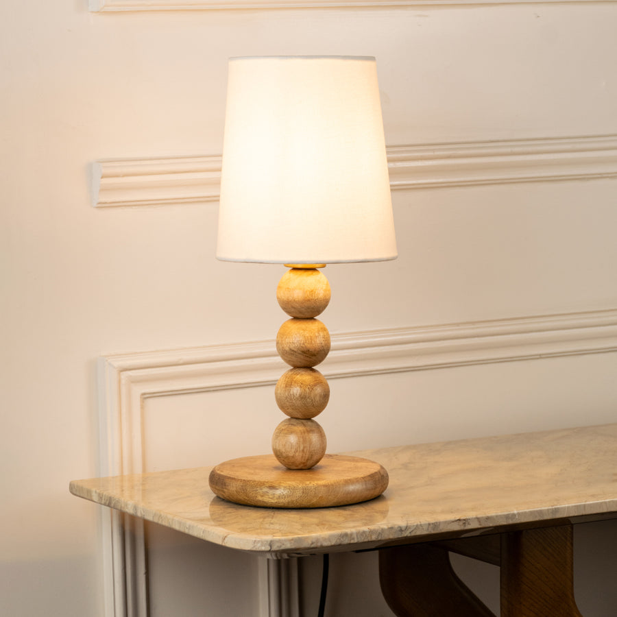 Closeup of table lamp with white fabric shade and sculpted base showcasing elegant design and warm lighting for bedroom decor styling.