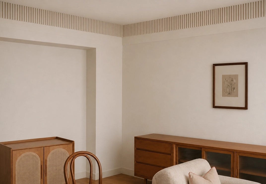 A styled interior corner featuring a mid-century modern wooden credenza and matching cabinet, a bentwood chair, a cream bouclé sofa, and a framed botanical print on a textured off-white wall.