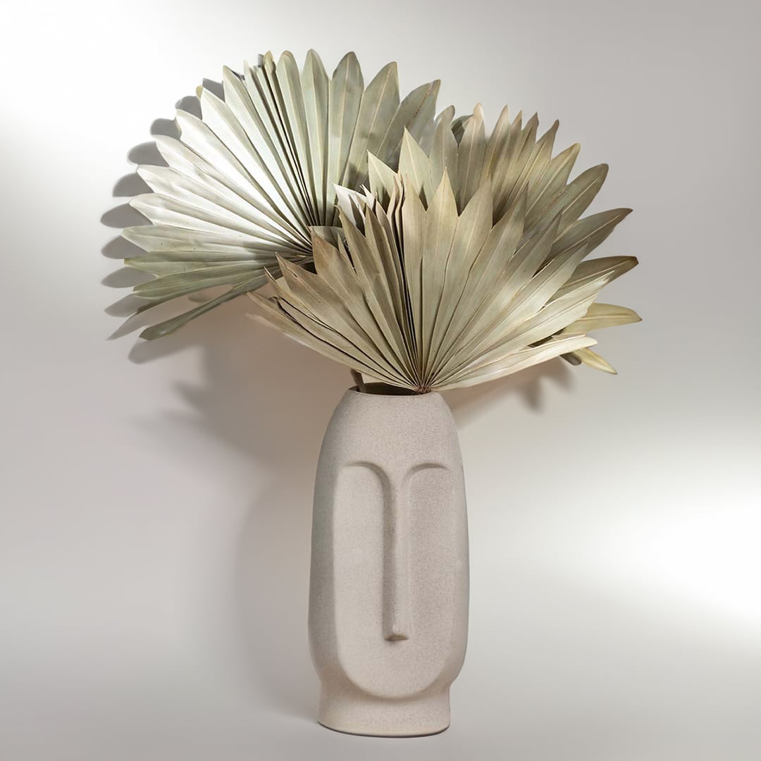 Beige ceramic face vase shown on a white background emphasizing its textured finish and minimal facial silhouette.