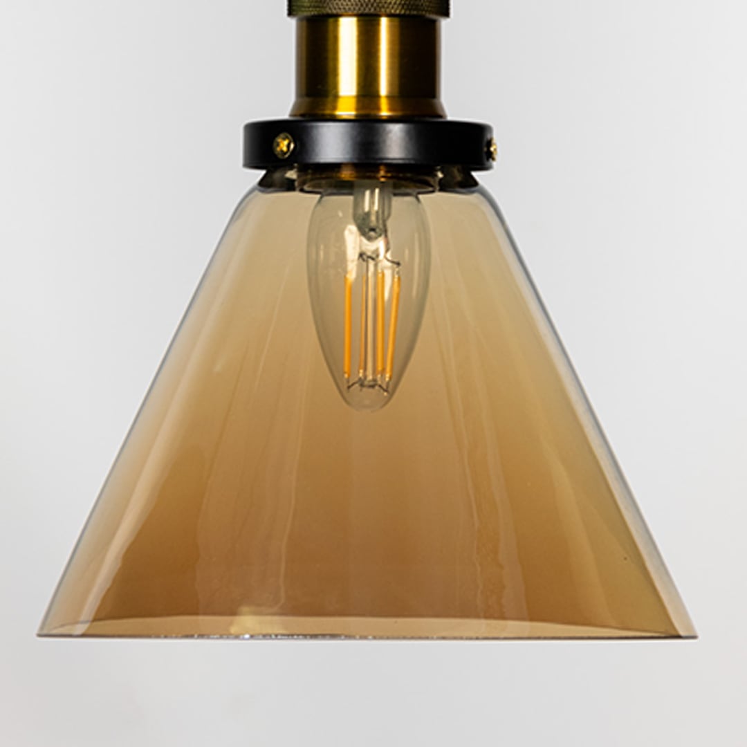 Closeup of amber glass pendant light with brass top and black fitting designed for modern home interior lighting.