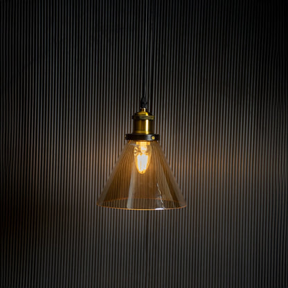 Amber glass pendant light glowing on black background with brass and black metal fitting for stylish home decor.