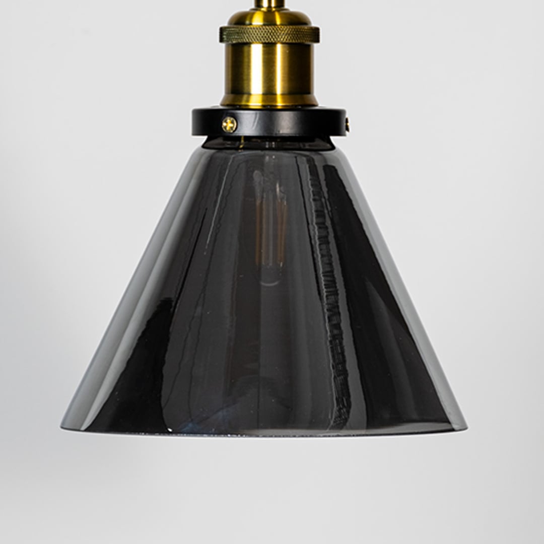 Closeup of smokey glass pendant light with brass top and black fitting designed for elegant home interior lighting.