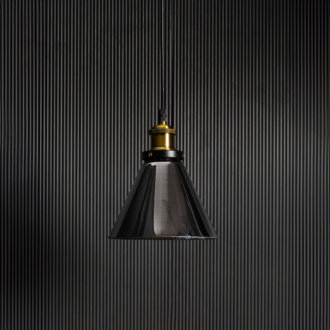 Smokey glass pendant light with bulb off on black background featuring brass and black fitting for modern decor.