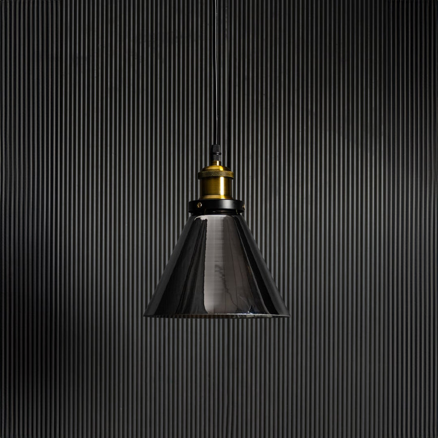 Smokey glass pendant light with bulb off on black background featuring brass and black fitting for modern decor.