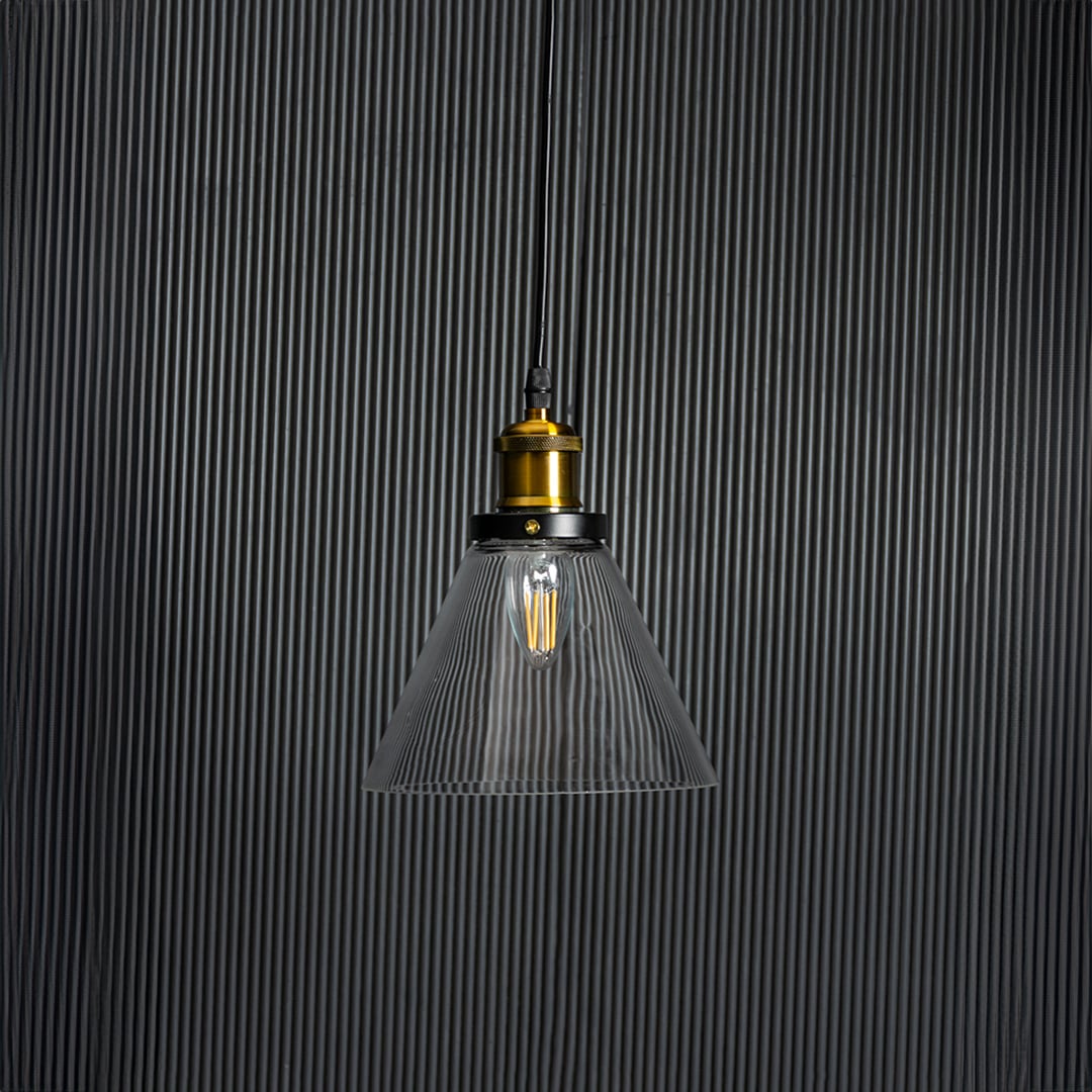 Glass pendant light with bulb off on black background highlighting transparent shade and brass black fitting.