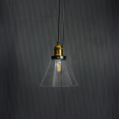 Glass pendant light with bulb off on black background highlighting transparent shade and brass black fitting.