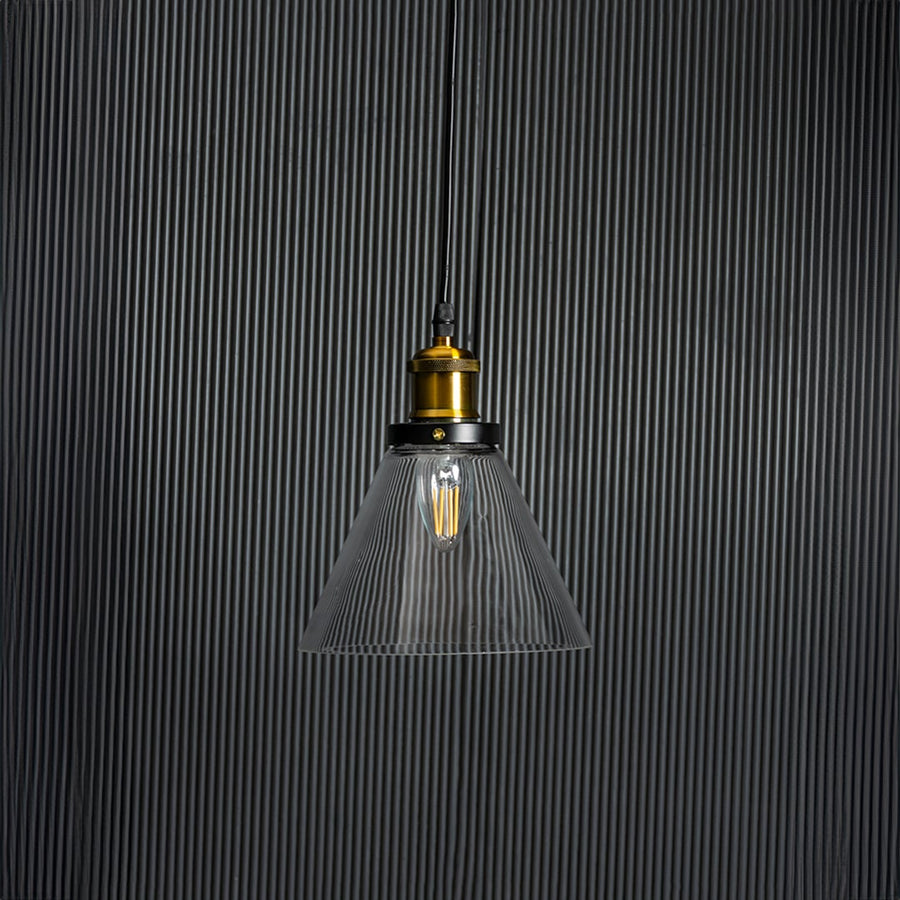 Glass pendant light with bulb off on black background highlighting transparent shade and brass black fitting.