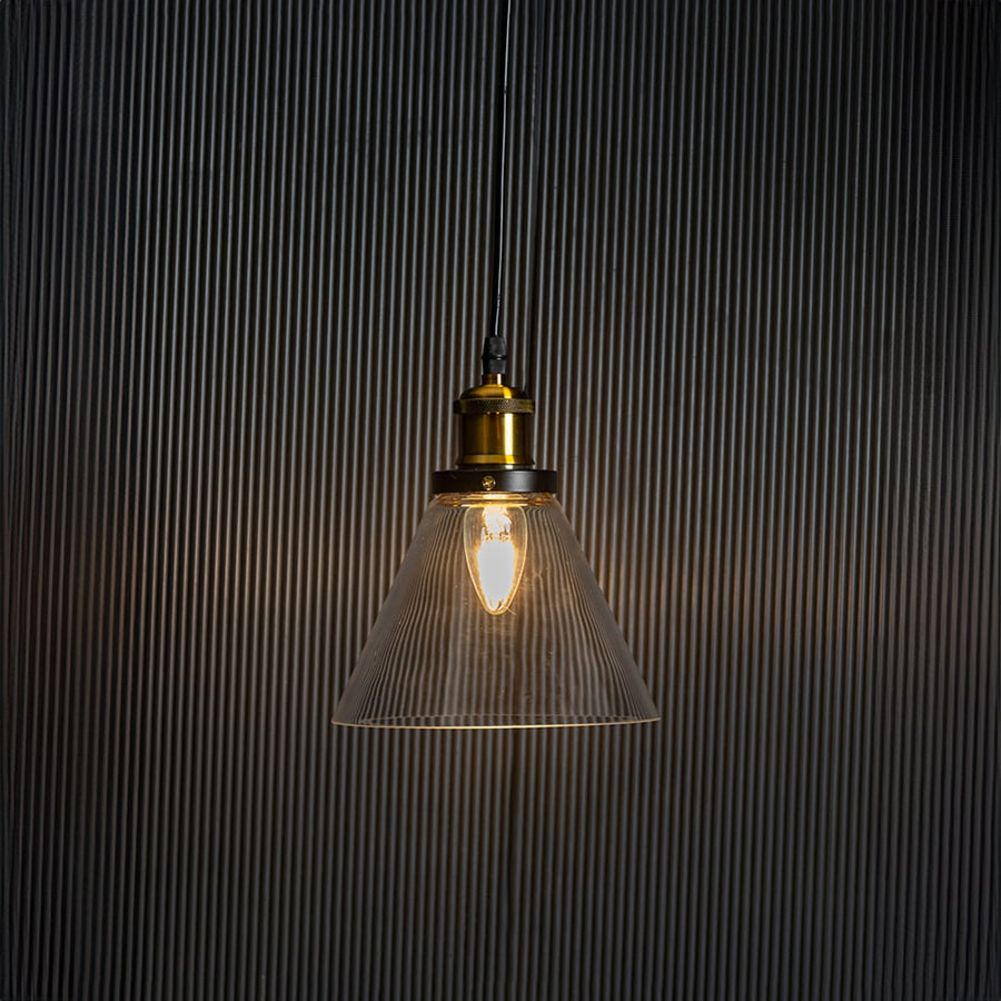 Stylish glass pendant light glowing on black background with modern brass and black metal fitting design.