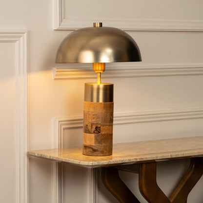 Stylish metal and wood table lamp with a golden dome shade and wooden cylinder base offering soft ambient light and sophisticated modern design.