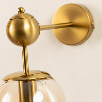 Closeup of gold metal and clear glass wall light for premium bedroom and modern decor styling spaces.

