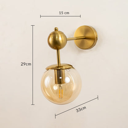Brushed gold wall light with amber glass globe measuring 29 cm height 15 cm width and 33 cm depth shown clearly for accurate wall placement.