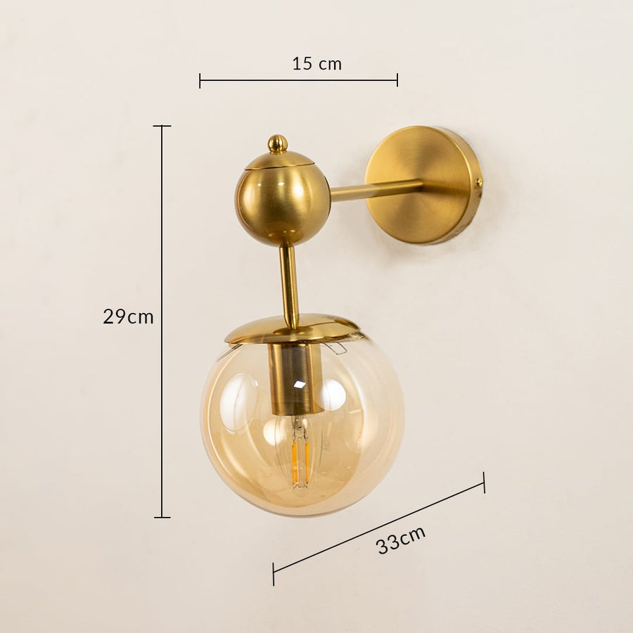 Brushed gold wall light with amber glass globe measuring 29 cm height 15 cm width and 33 cm depth shown clearly for accurate wall placement.