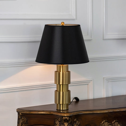 Black metal table lamp with black fabric shade displayed on a carved wooden console table creating luxury ambient lighting.