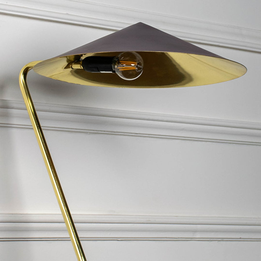 Closeup of gold metal table lamp with dark brown conical shade showing sleek angled stand and contemporary design.