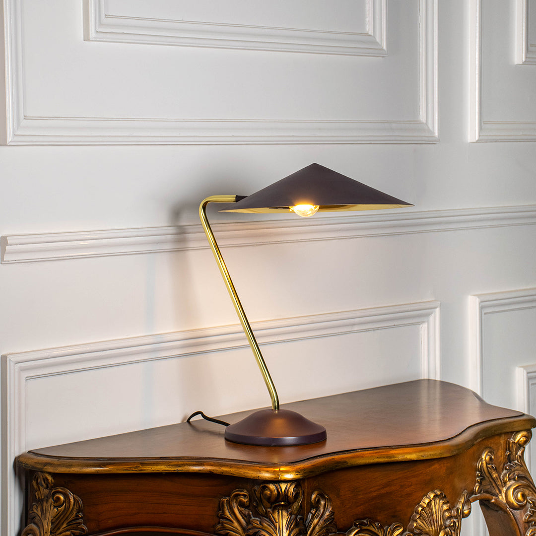 Contemporary brass desk lamp with angular metal shade providing directed task lighting for office and reading desks.
