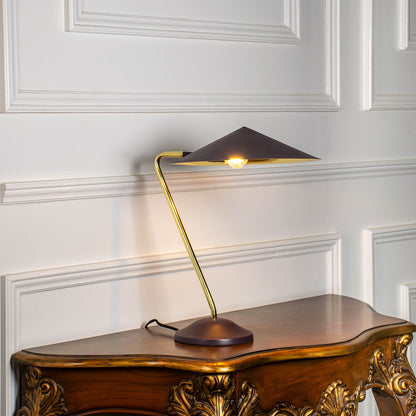 Contemporary brass desk lamp with angular metal shade providing directed task lighting for office and reading desks.