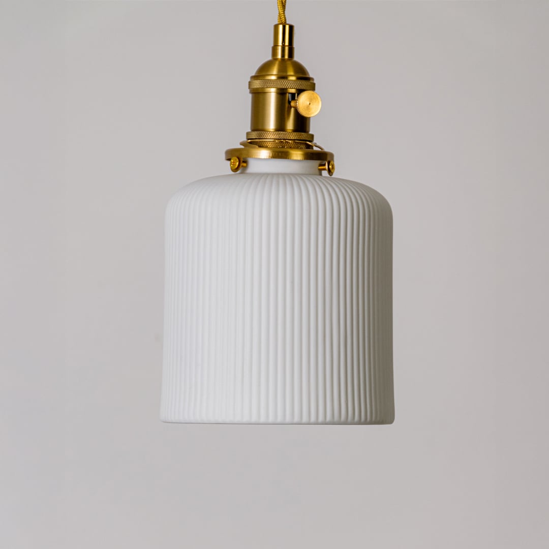 Closeup of ribbed white glass pendant light showing tall textured shade and gold metal holder for elegant interior decor.