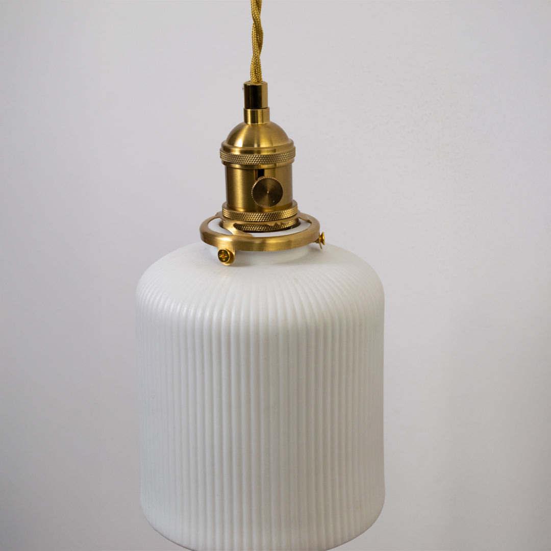 Closeup pendant light in gold metal finish with ribbed glass shade for kitchen or dining decor lighting white background.