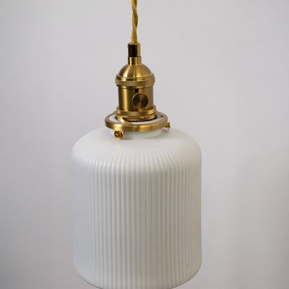 Closeup pendant light in gold metal finish with ribbed glass shade for kitchen or dining decor lighting white background.