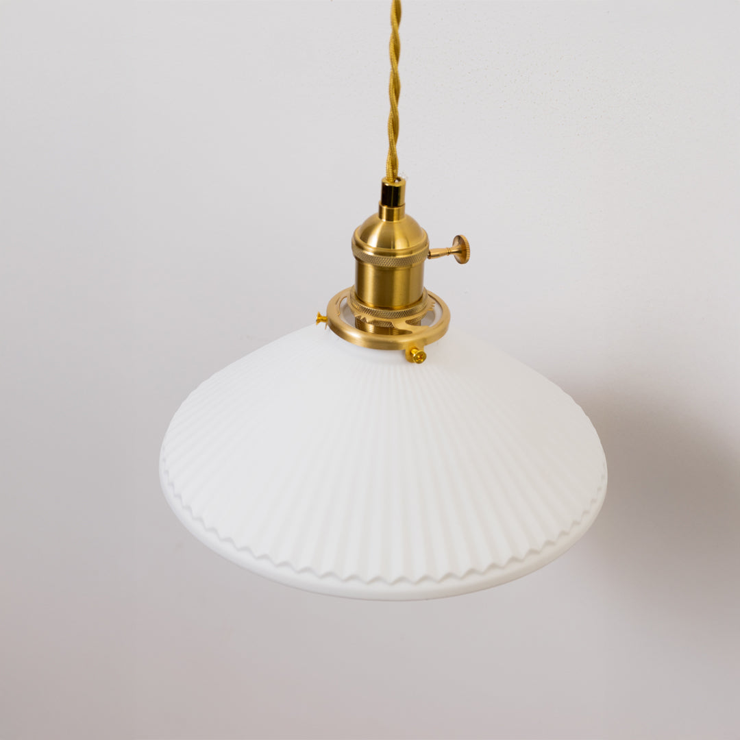 Closeup pendant light in gold metal finish with wide glass shade for kitchen or dining decor lighting white background.