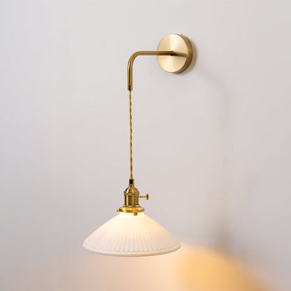 Gold metal wall light with white ribbed shade glowing softly on white background for elegant vintage inspired home decor.