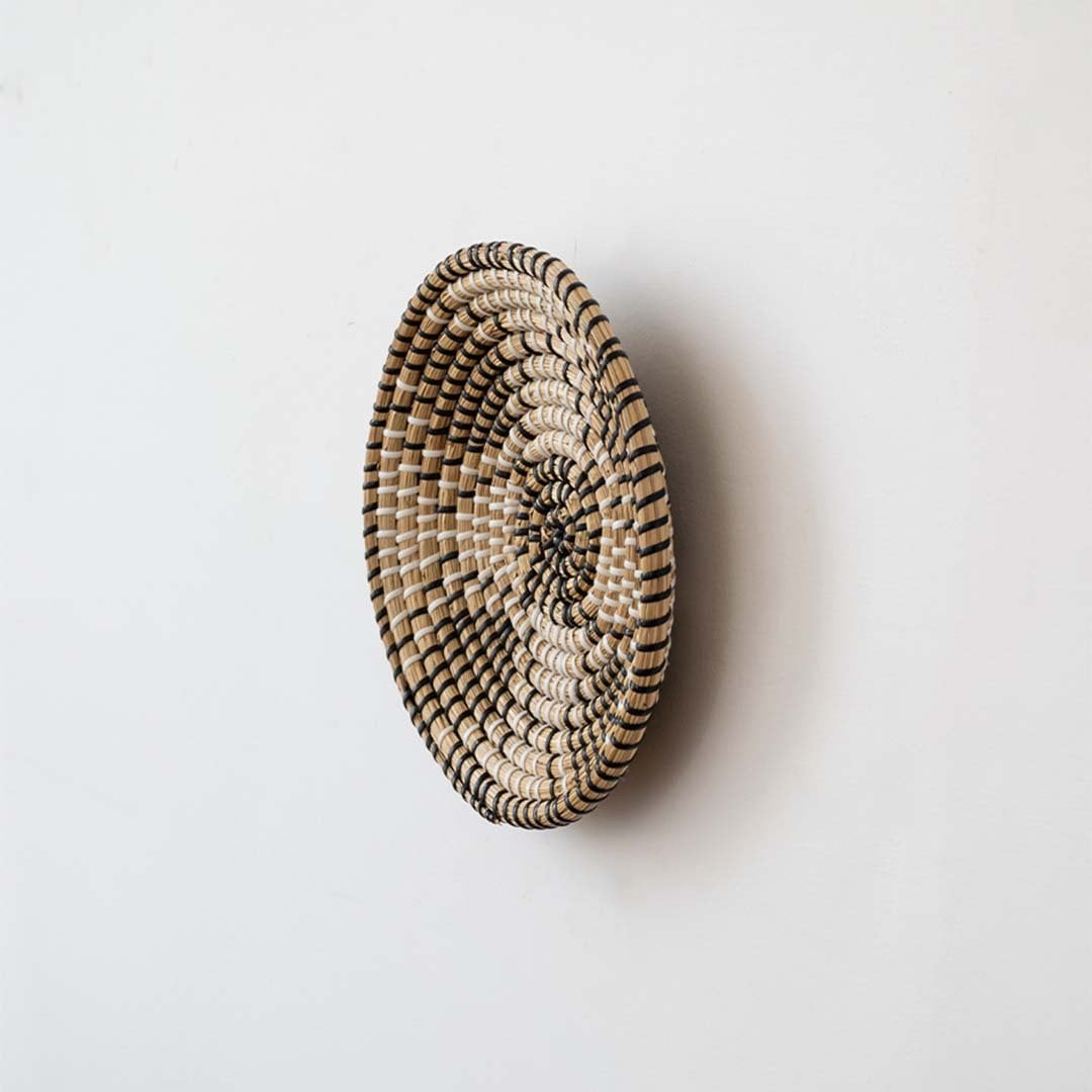 Side view of round woven wall basket highlighting slim profile layered weave depth and handcrafted natural fiber texture.