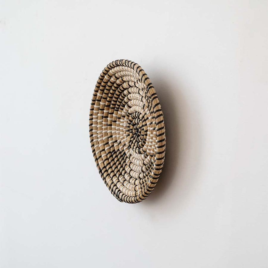 Side view of round woven wall basket highlighting slim profile layered weave depth and handcrafted natural fiber texture.