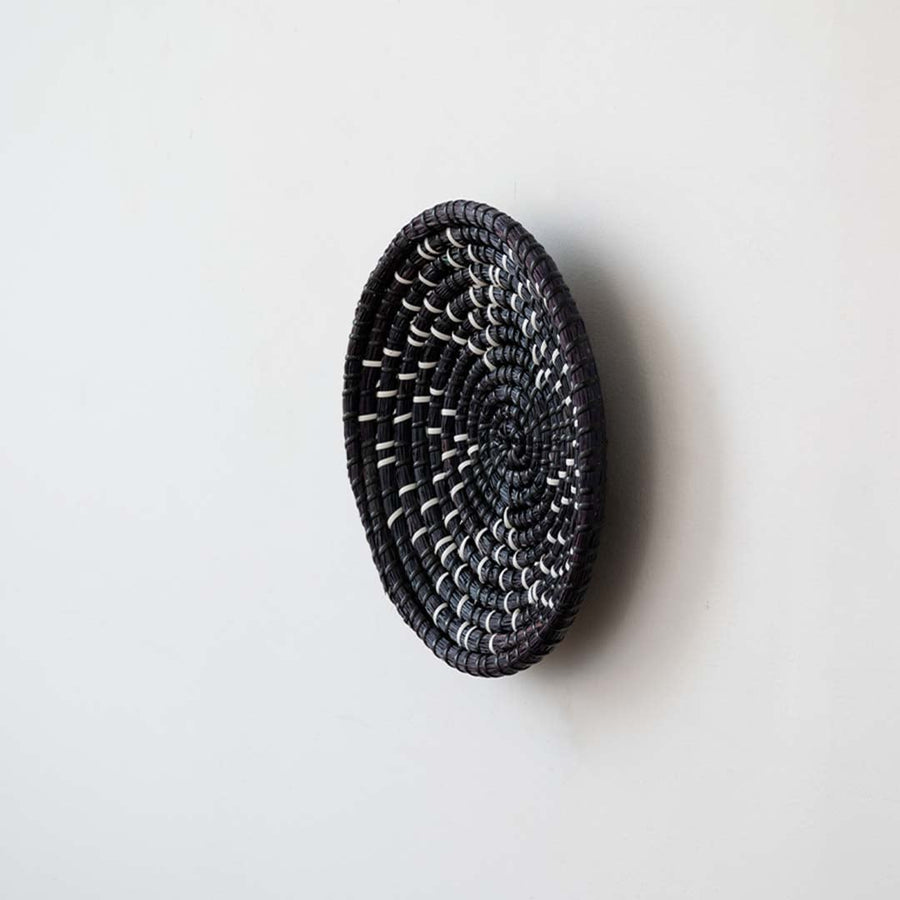 Side view of handwoven black wall basket made of rustic natural fiber with boho style for wall decor.