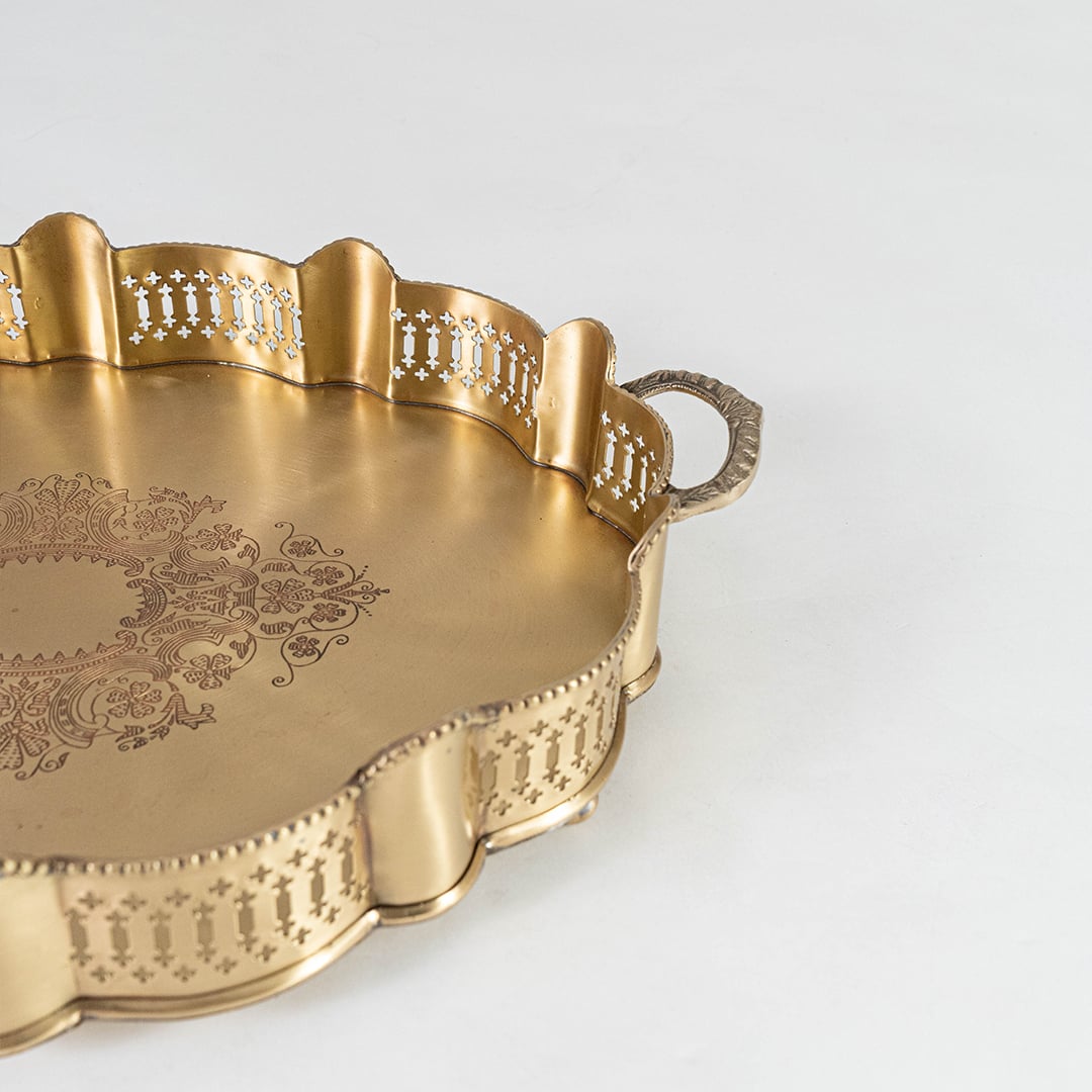 Zoomed view of decorative gold brass tray handle and rim displaying carved patterns and elegant vintage-style design.