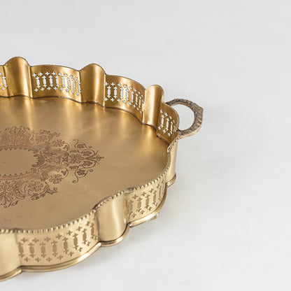 Zoomed view of decorative gold brass tray handle and rim displaying carved patterns and elegant vintage-style design.