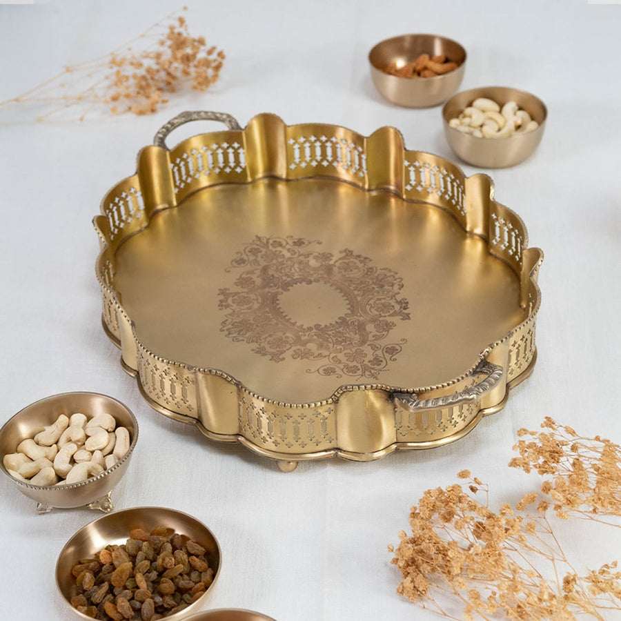Round gold brass serving tray with ornate edge and floral center engraving photographed on white background for clarity.