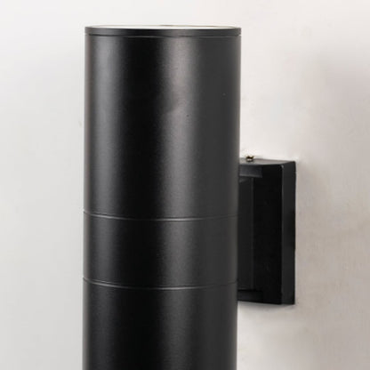 Closeup of tall black metal cylindrical outdoor wall light showing smooth matte finish and modern exterior design.