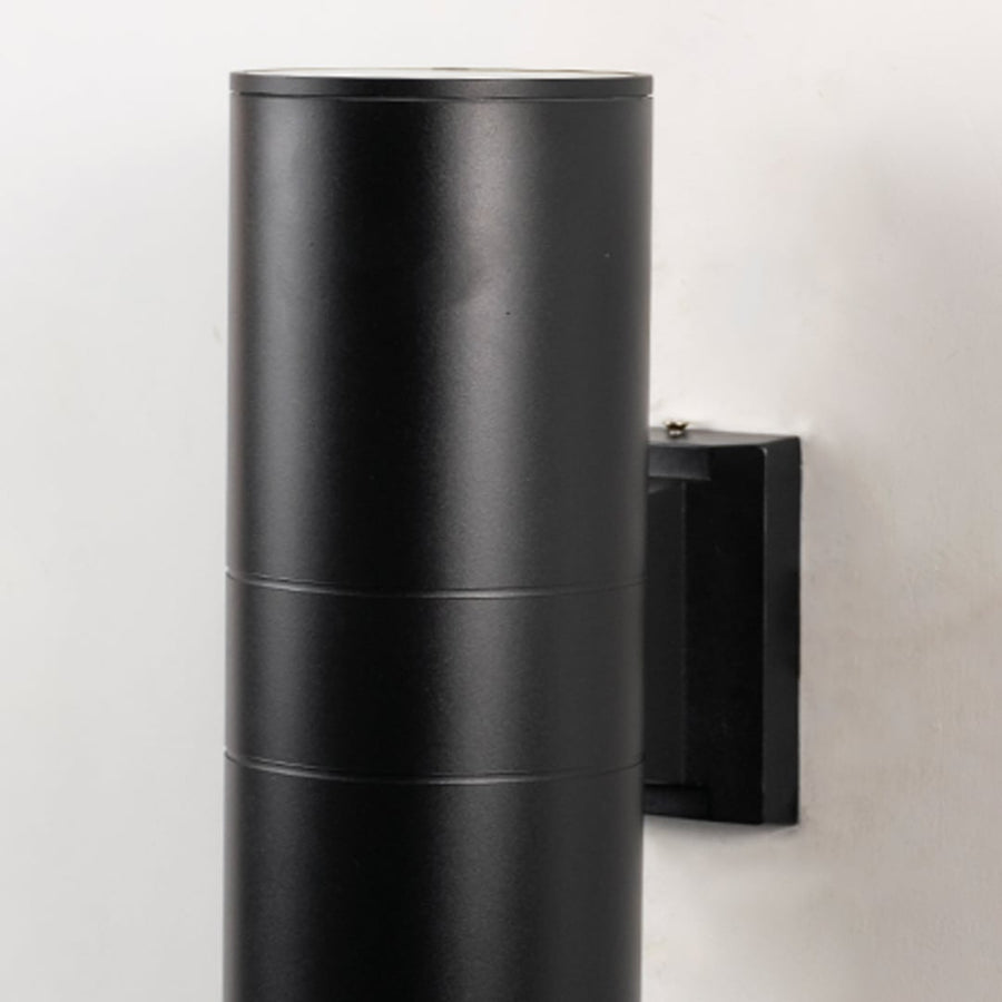 Closeup of tall black metal cylindrical outdoor wall light showing smooth matte finish and modern exterior design.