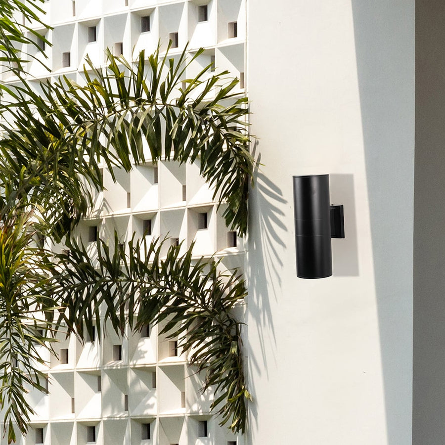Black metal cylindrical outdoor wall light enhancing exterior entryway decor with sleek modern minimalist lighting design.