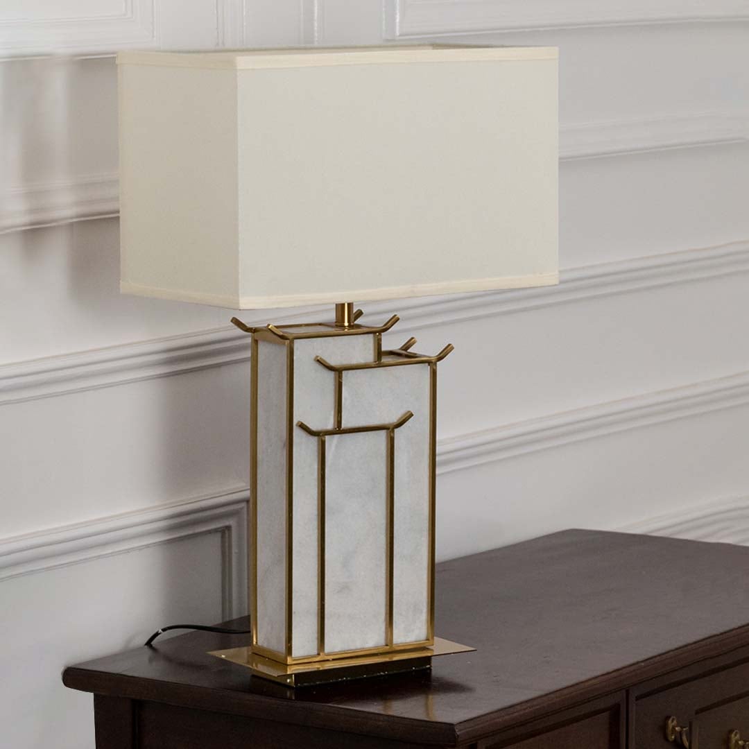 White rectangular shade marble and gold geometric table lamp on wooden sideboard with light off for elegant modern décor.
