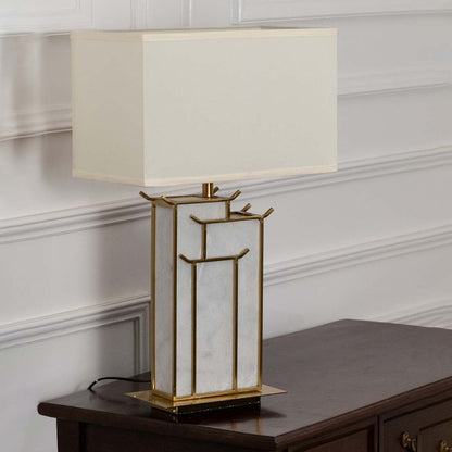 White rectangular shade marble and gold geometric table lamp on wooden sideboard with light off for elegant modern décor.